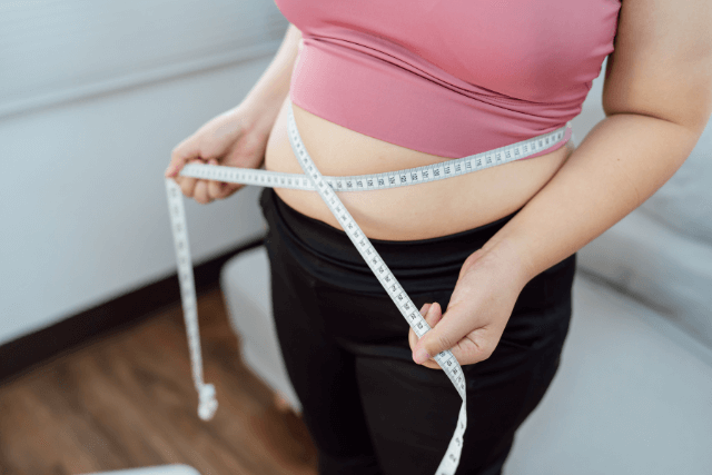 woman with a masuring tape in the process of Losing Belly Fat